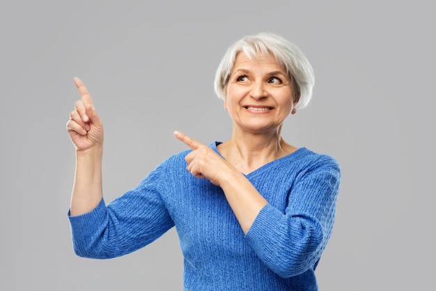 smiling senior woman pointing fingers to something