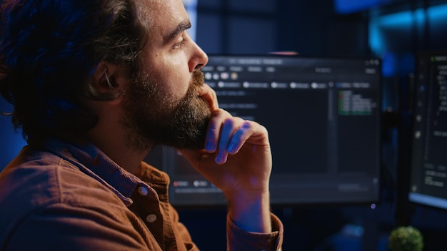 Software engineer puzzled in front of computer screen while writing complex code