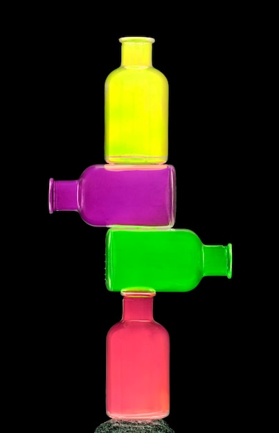 Stack of colorful bottles against black background