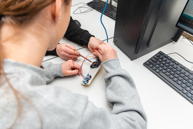 Teacher helping his teen student with diy robot on stem education classStudent In After School Computer Coding Class Building And Learning To Program Robot VehicleArduino Ultrasonic installation
