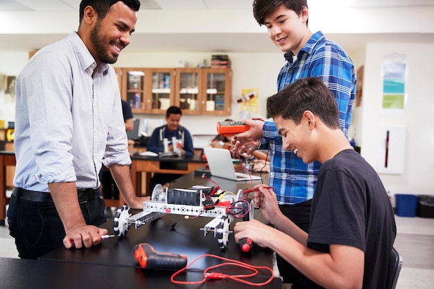 teacher with male pupils building robotic vehicle in science lesson