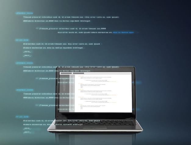 technology and programming concept - laptop computer with coding on screen over gray background
