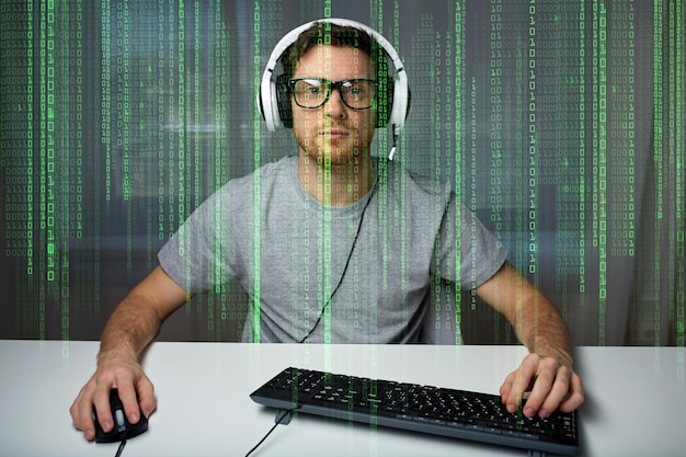technology, gaming, entertainment, let&amp;#39;s play and people concept - young man in headset and eyeglasses with pc computer playing game at home and streaming playthrough or walkthrough video