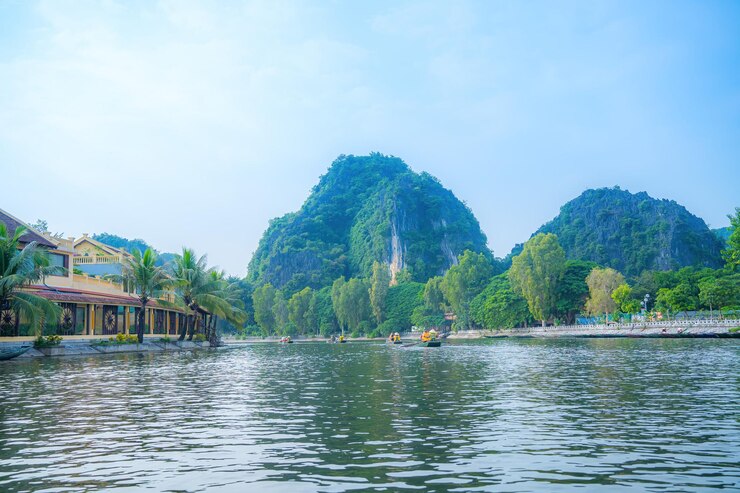 Photo tourists traveling in boats along the ngo dong river at the tam coc portion ninh binh province vietnam rowers using their feet to propel oars landscape formed by karst towers and rice fields