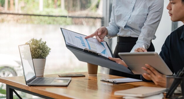 two asian businessmen met in the office and pointed to analysis charts and graphs of business growth and financial performance