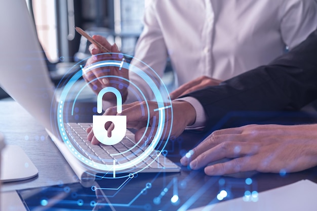 Two businesspeople in formal wear working on the project to protect cyber security of international company using laptop Padlock Hologram icons Teamwork concept
