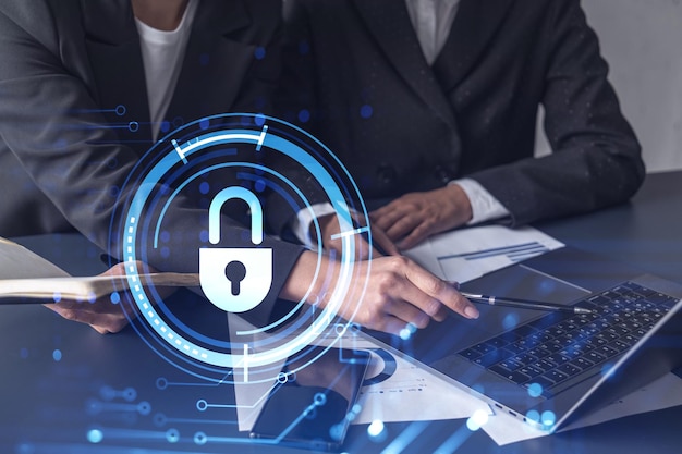 Two businesswomen working on the project to protect cyber security of international company Padlock Hologram icons over the table with documents