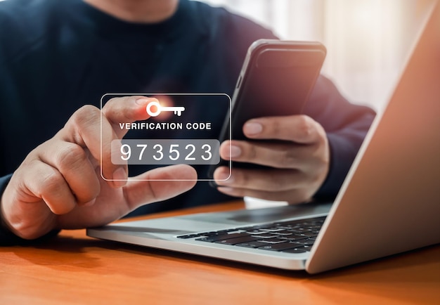 Two factor authentication or 2FA concept Verification code with key icon press by man hand while using smart phone and laptop computer for validate password secure steps cyber security technology