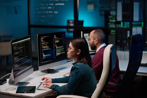 Two People Writing Code in Blue Lights