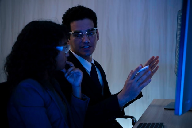 Two software developers collaborating at night focusing on code review and debugging process on a computer screen representing teamwork innovation and modern software development workflow