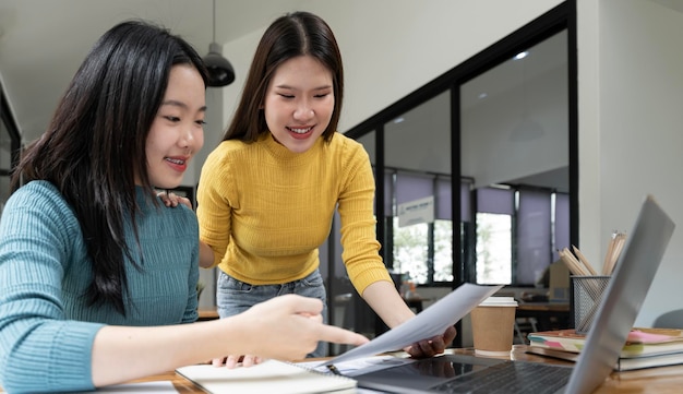 Two young Asian business woman colleagues discuss working with new startup project idea presentation analyze plan marketing and investment in the office
