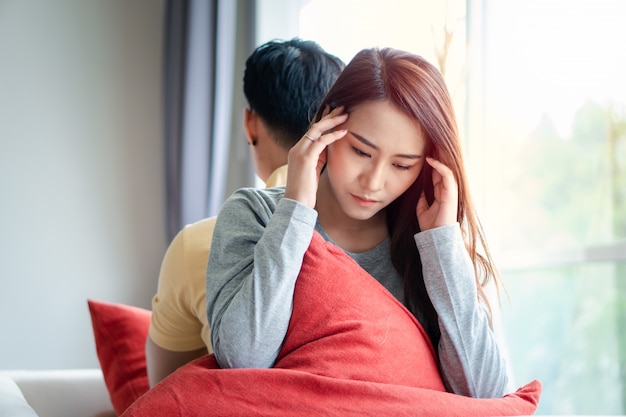 unhappy couple sitting behind each other on the couch and avoid talking