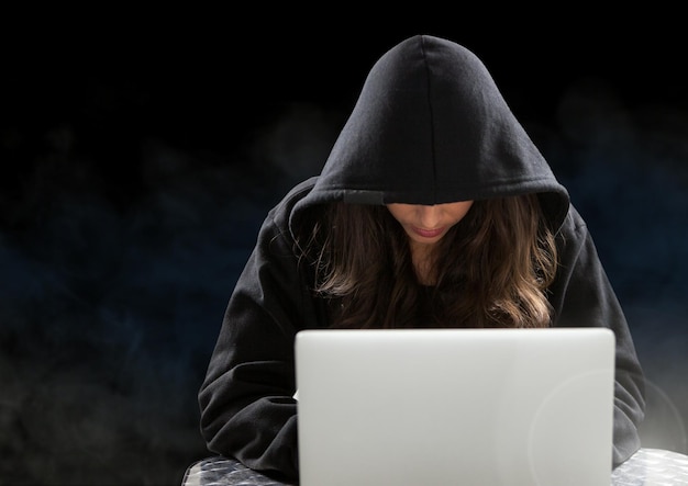 Woman hacker working on laptop in front of black background