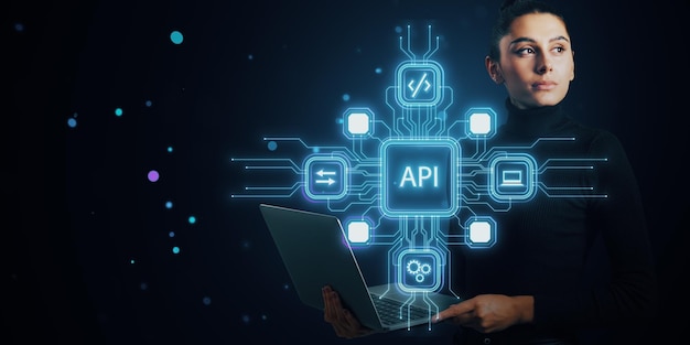 Woman holding laptop with holographic API icons and symbols on dark blue digital background