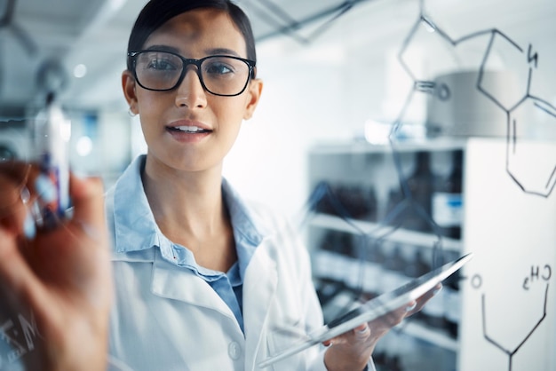 Woman scientist and glass board equation and formula with problem solving and scientific study in lab Female doctor writing with tablet chemistry and science innovation with medical research