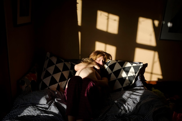 woman sleeping with daughter on bed at home