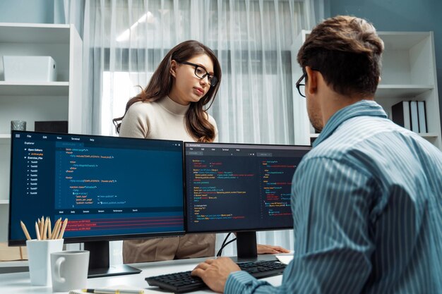 Woman standing opposite to man programmer working on desk to discuss postulate