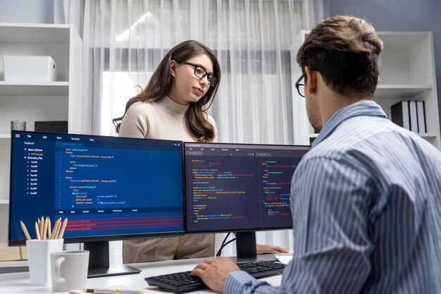 Woman standing opposite to man programmer working on desk to discuss Postulate