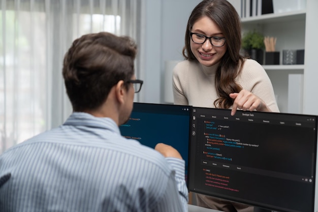 woman standing opposite to man programmer working on desk to discuss postulate