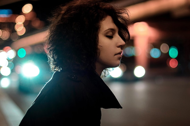 woman with closed eyes in illuminated city