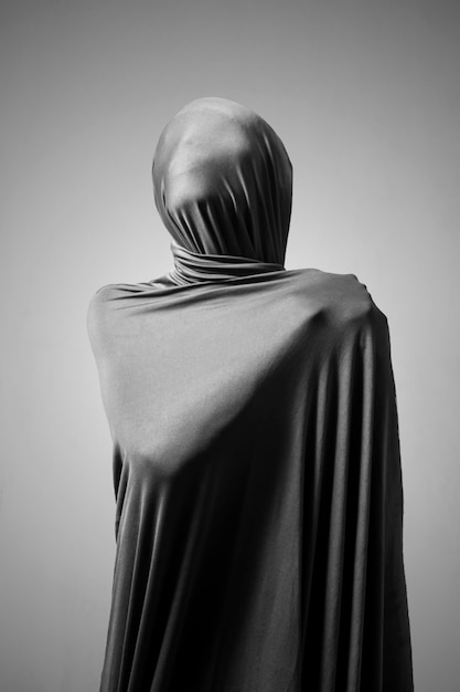 woman wrapped in fabric standing against gray background