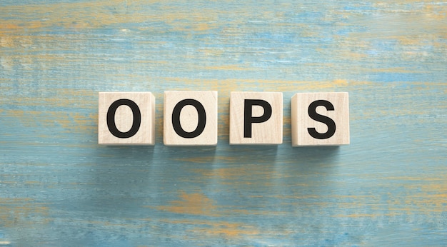 Word OOPS. Wooden small cubes with letters isolated on blue background with copy space available. Concept image.