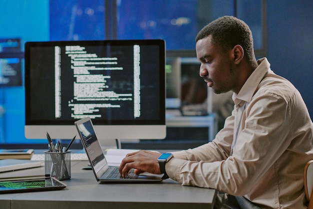 Young black man typing on laptop in cybersecurity office
