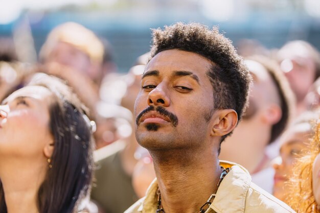 young brunette man standing in a crowd outdoors