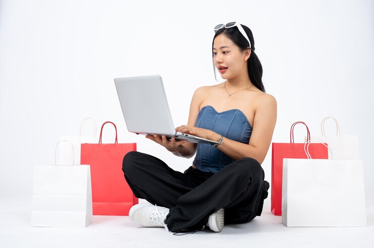 Photo young elegant and happy asian woman enjoying using online shopping website on her laptop computer