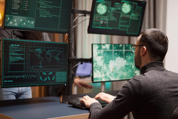 young hacker making a dangerous virus for cyber attacks on computer with multiple screens.
