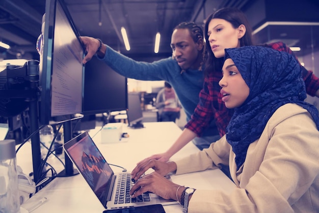 young multiethnics business team of software developers working together using laptop computer while writing programming code at modern startup office