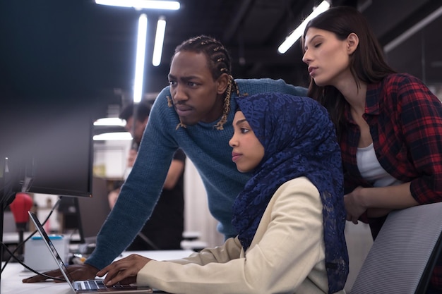 young multiethnics business team of software developers working together using laptop computer while writing programming code at modern startup office