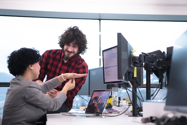 young software developers couple using laptop and desktop computer while writing programming code at modern creative startup office