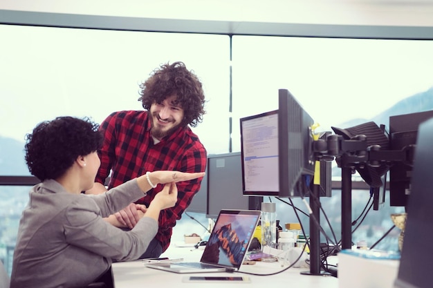 young software developers couple using laptop and desktop computer while writing programming code at modern creative startup office