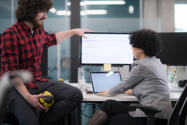 young software developers couple using laptop and desktop computer while writing programming code at modern creative startup office