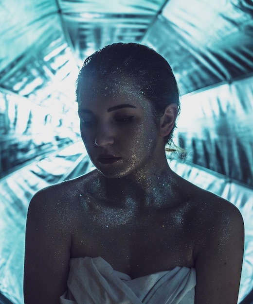young woman covered with glitter against curtain