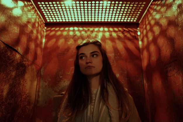 young woman looking away against metallic built structure