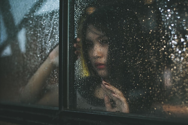 young woman sitting in car during rainy season