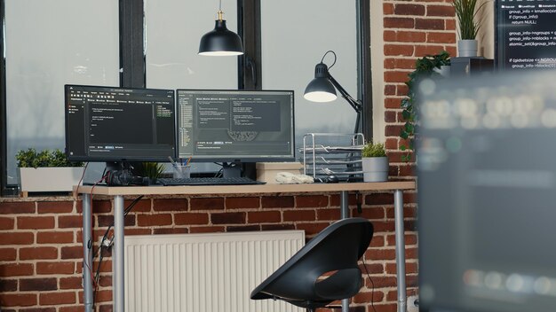 desk with multiple computer monitors displaying parsing code and programming language compiling in empty software developing agency office. servers cloud computing big data algorithms.