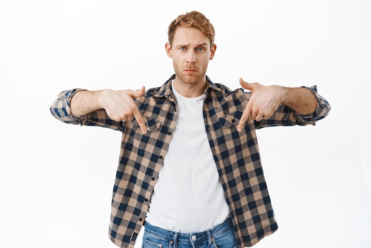 Miễn phí Photo doubtful man asking your opinion what do you think redhead guy pointing fingers down showing advertisement logo bellow looking uncertain standing over white background