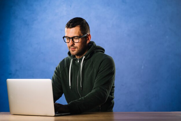 hacker with glasses looking at laptop