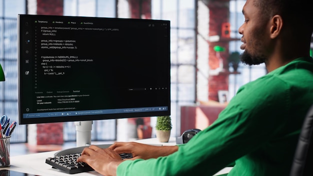 male programmer types code on computer and running script