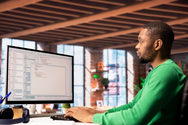 man in home office looking at pc screen executing programming code