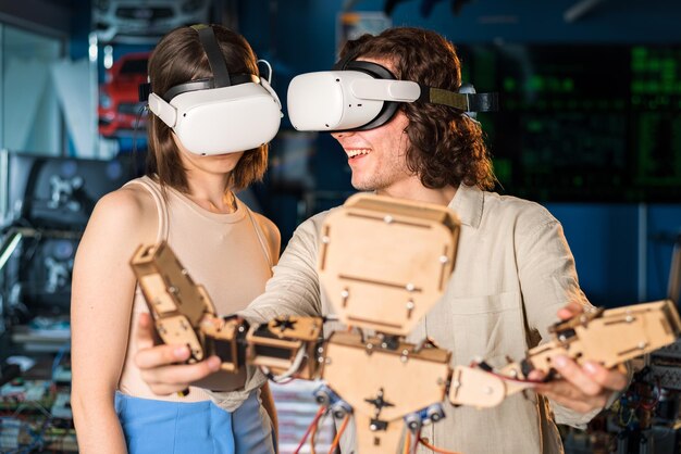 Người đàn ông và phụ nữ trẻ đeo kính bảo hộ đang thực hiện các thí nghiệm về robot trong phòng thí nghiệm Robot