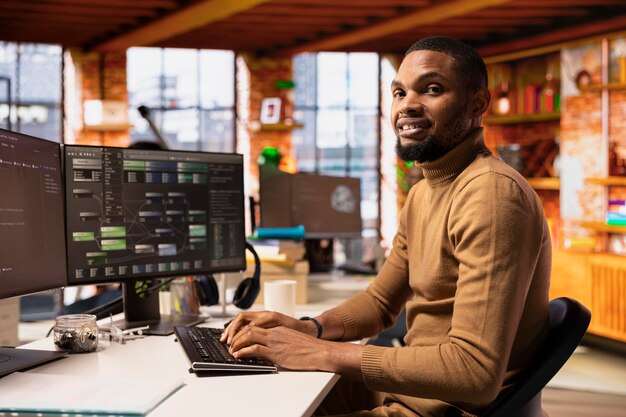 portrait of smiling it expert using pc in startup office to implement algorithms