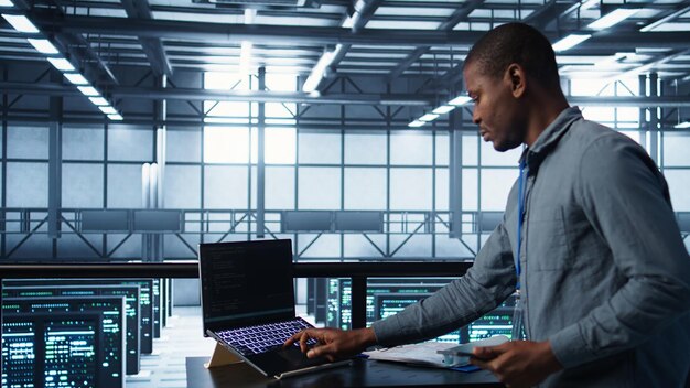 Technician in data center with laptop and tablet integrating AI technology