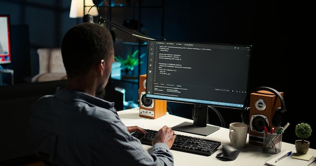 African american expert at desk using pc for programming and data analysis