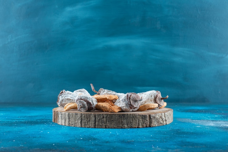 Ilmainen Kuva dried apple rings and persimmon on a board on the blue surface