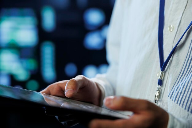 Engineer in data center using tablet to prevent system overload close up Employee in server room ensuring there is enough network connectivity for smooth operations blurry background