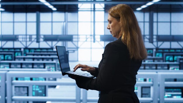 IT-asiantuntija valvoo palvelininfrastruktuuria palvelinkeskuksessa kannettavan tietokoneen avulla.